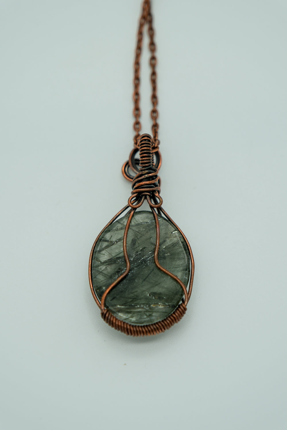Necklace with a green stone pendant on a light gray background