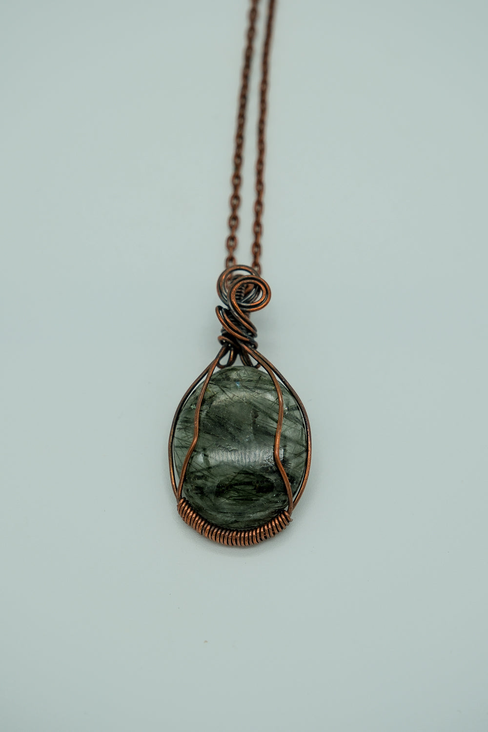 Necklace with a green stone pendant on a light gray background