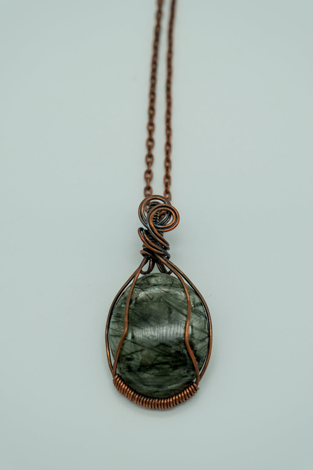 Necklace with a green stone pendant on a light gray background