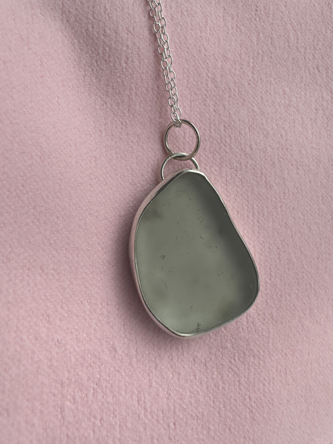 Necklace with a sea glass pendant on a pink background