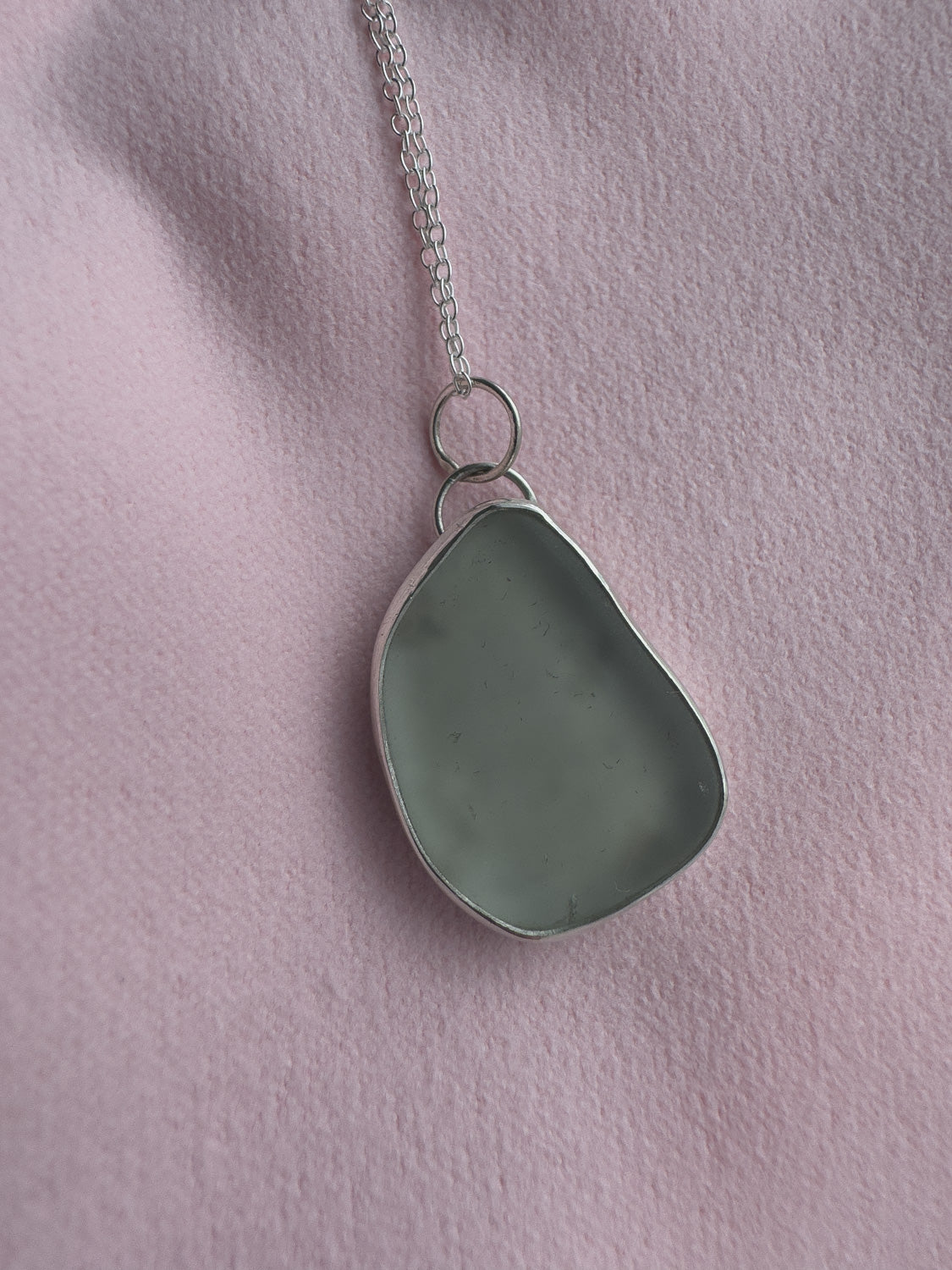 Necklace with a sea glass pendant on a pink background