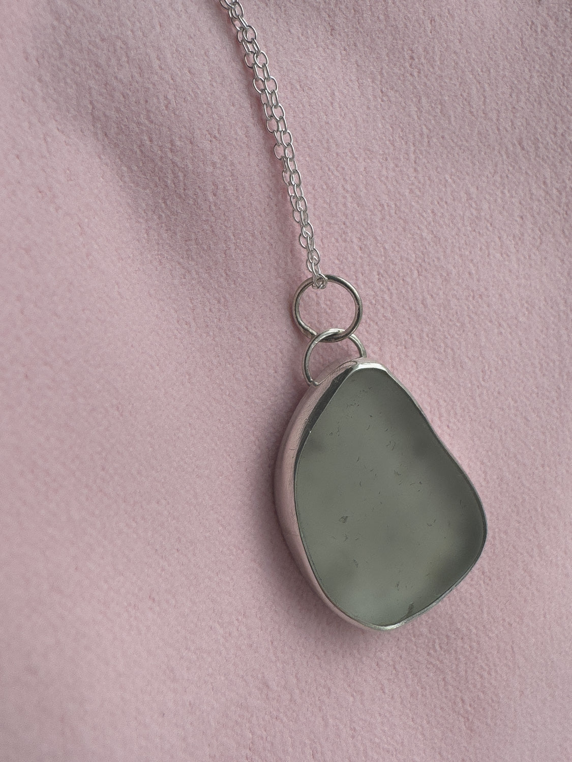 Necklace with a teardrop-shaped pendant on a pink background
