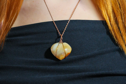 Necklace with a large, round, beige pendant worn by a person with red hair.