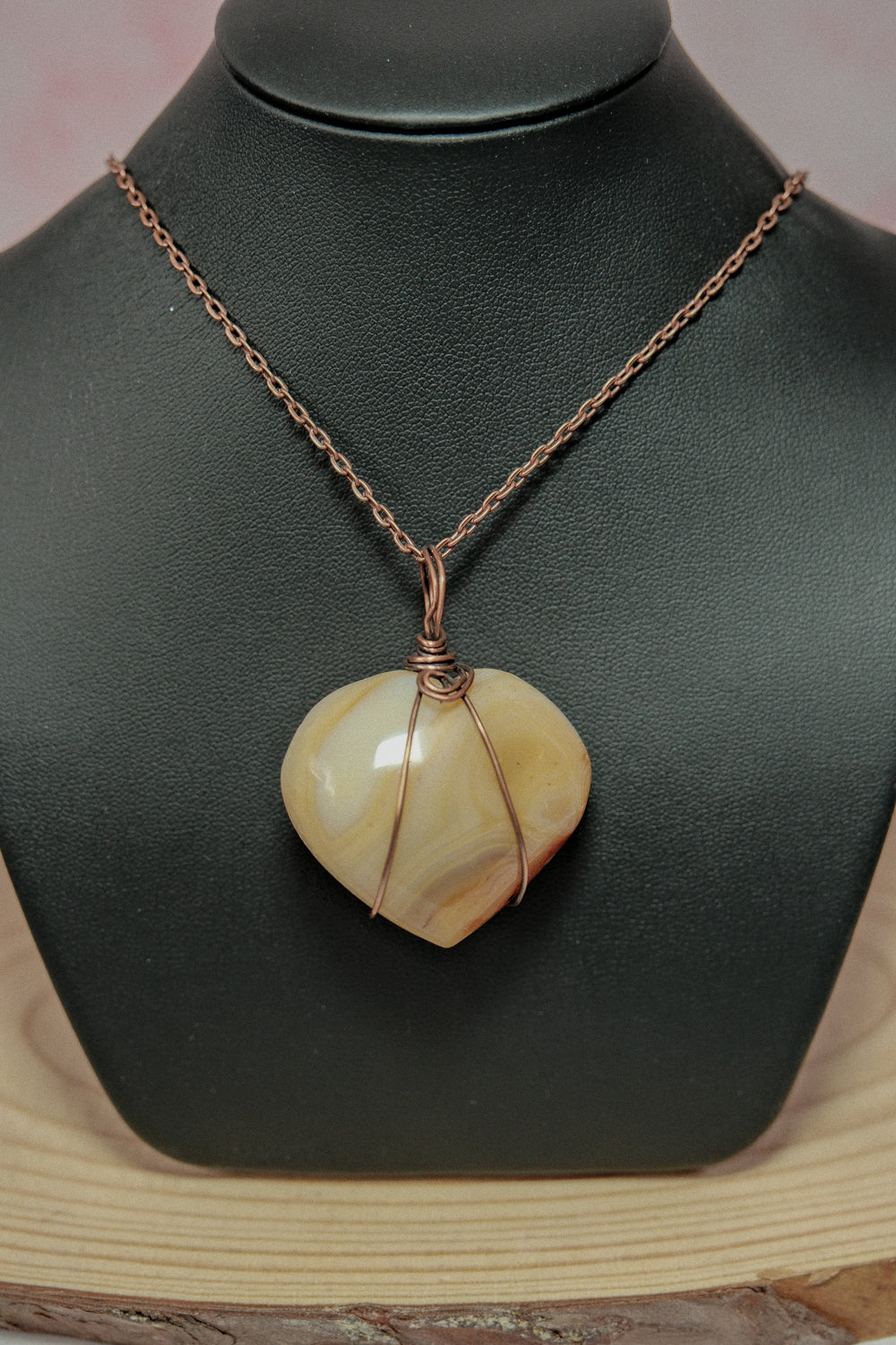 Necklace with a heart-shaped pendant on a black mannequin bust.