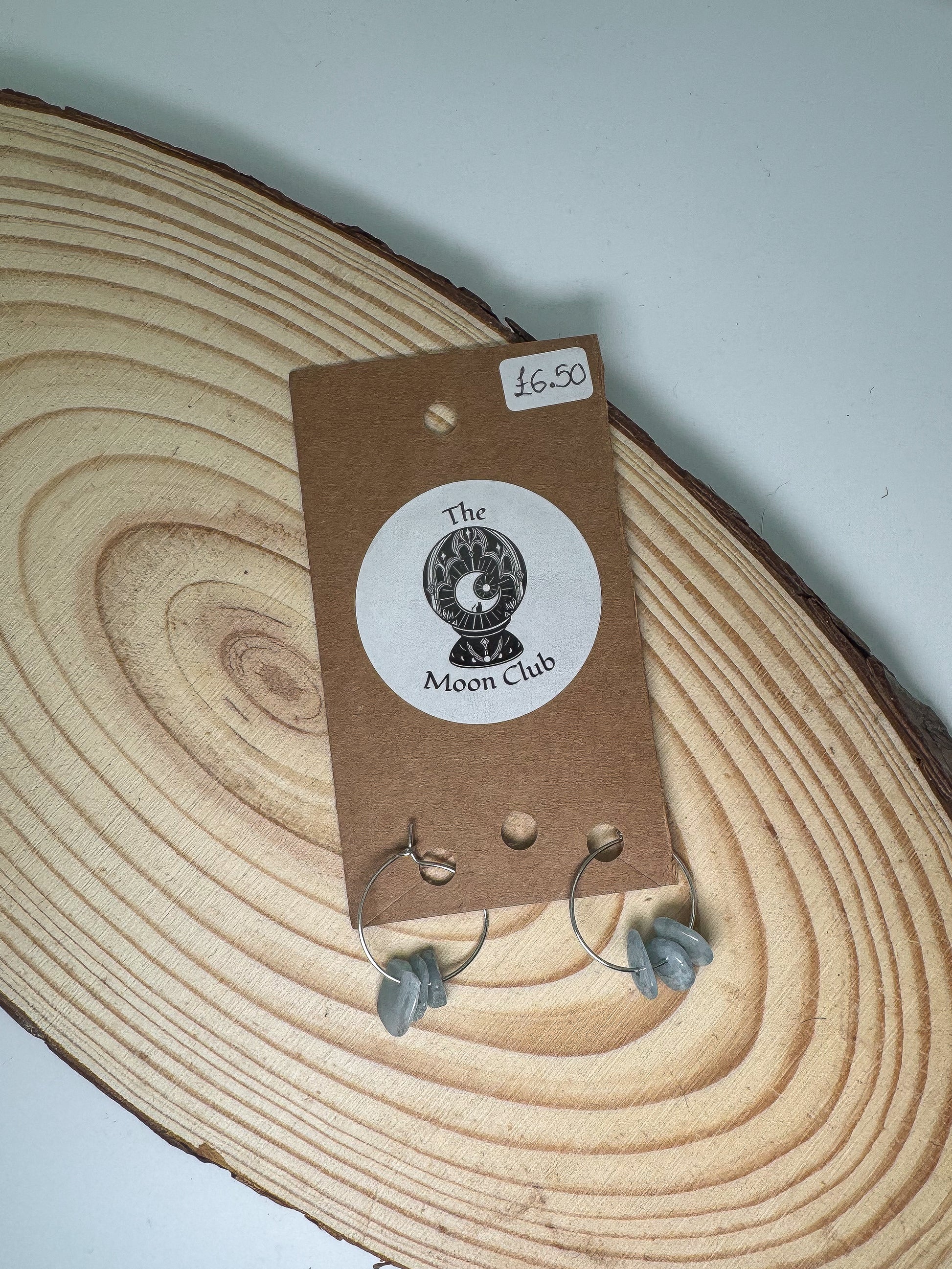 Earring card with aquamarine earrings on a wooden surface