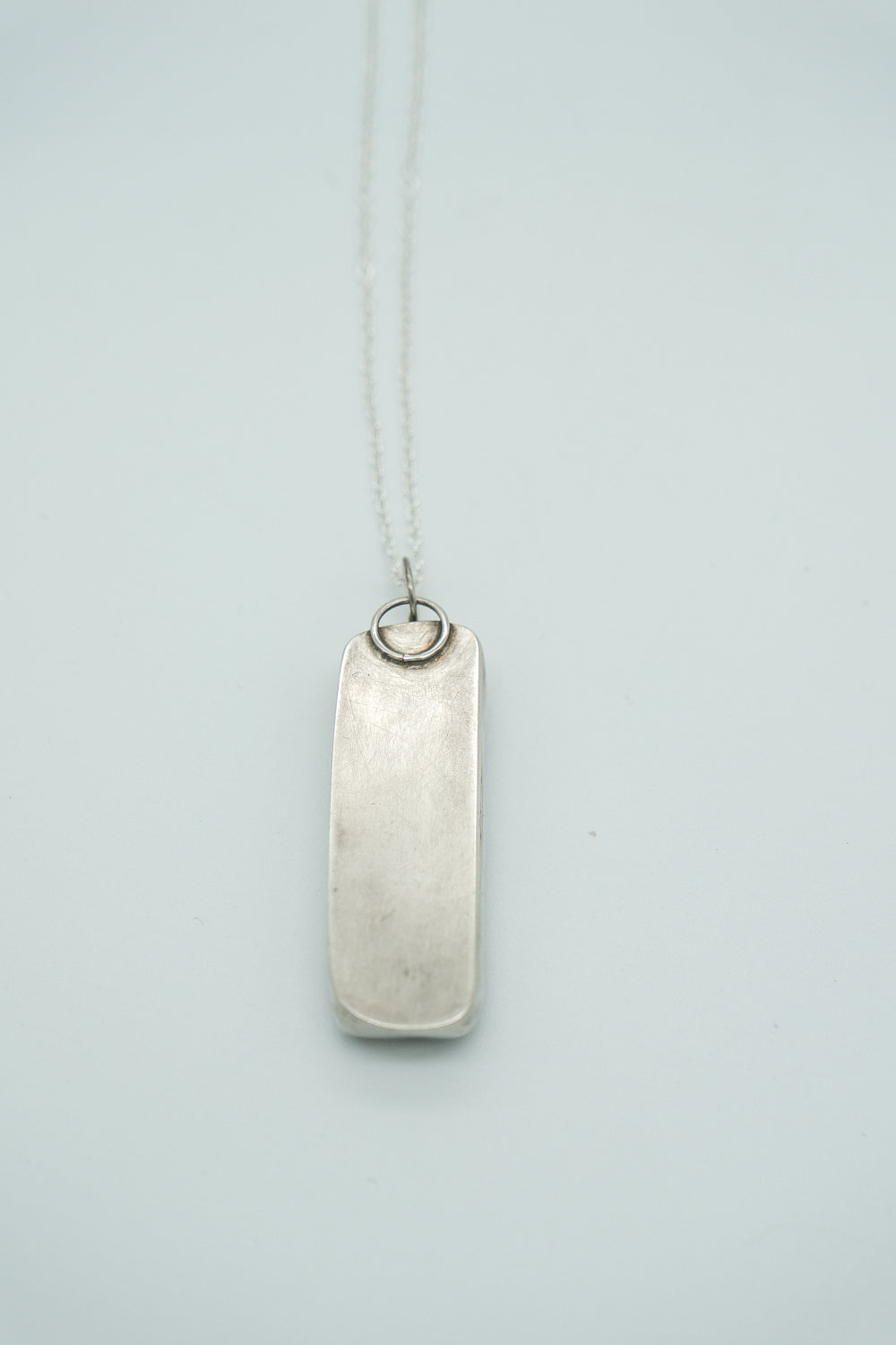 Silver pendant necklace on a light gray background