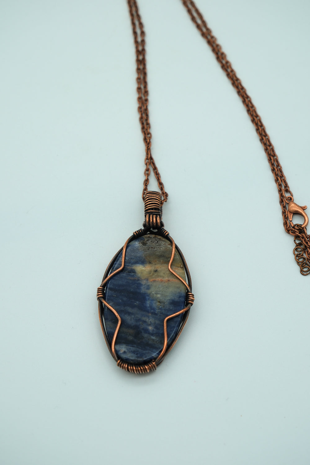 Necklace with a blue stone pendant on a light blue background