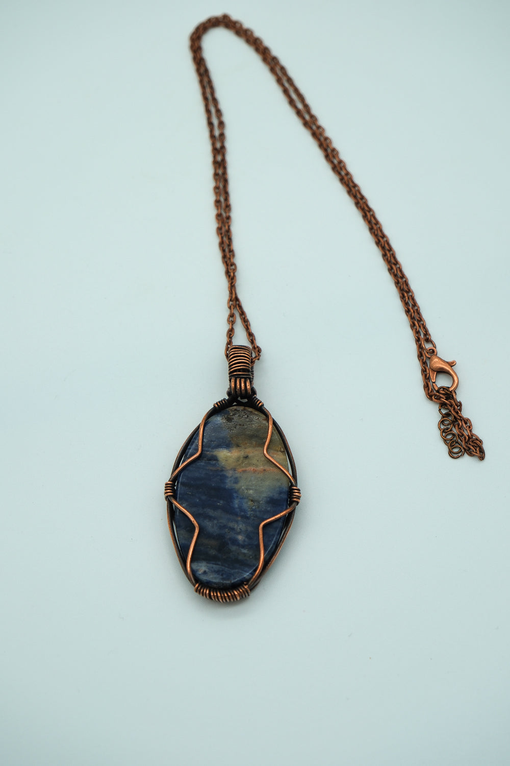 Necklace with a blue stone pendant on a light blue background