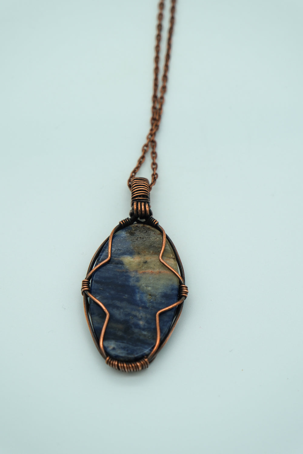 Necklace with a blue stone pendant on a light blue background