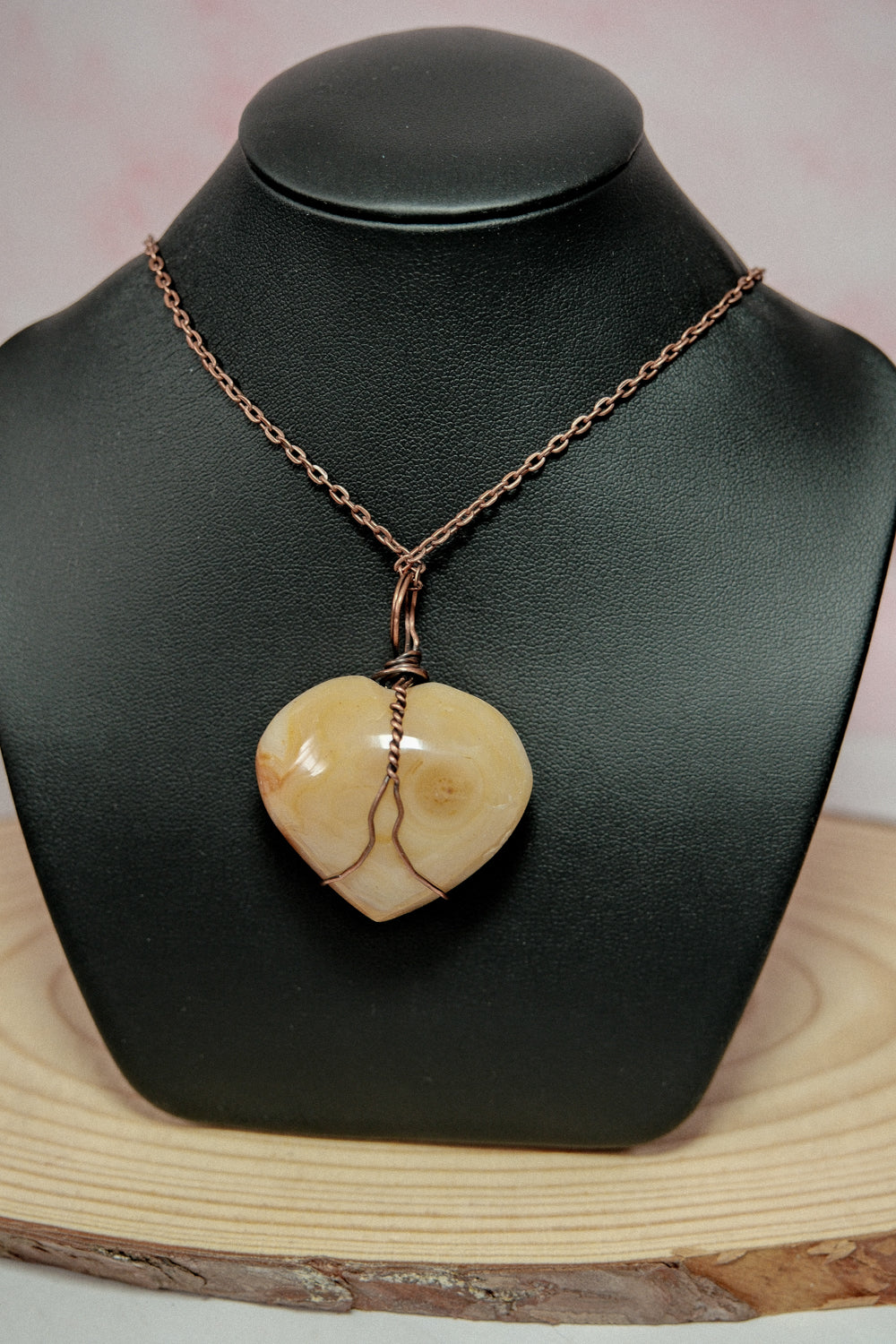 Necklace with a heart-shaped pendant on a black mannequin bust.
