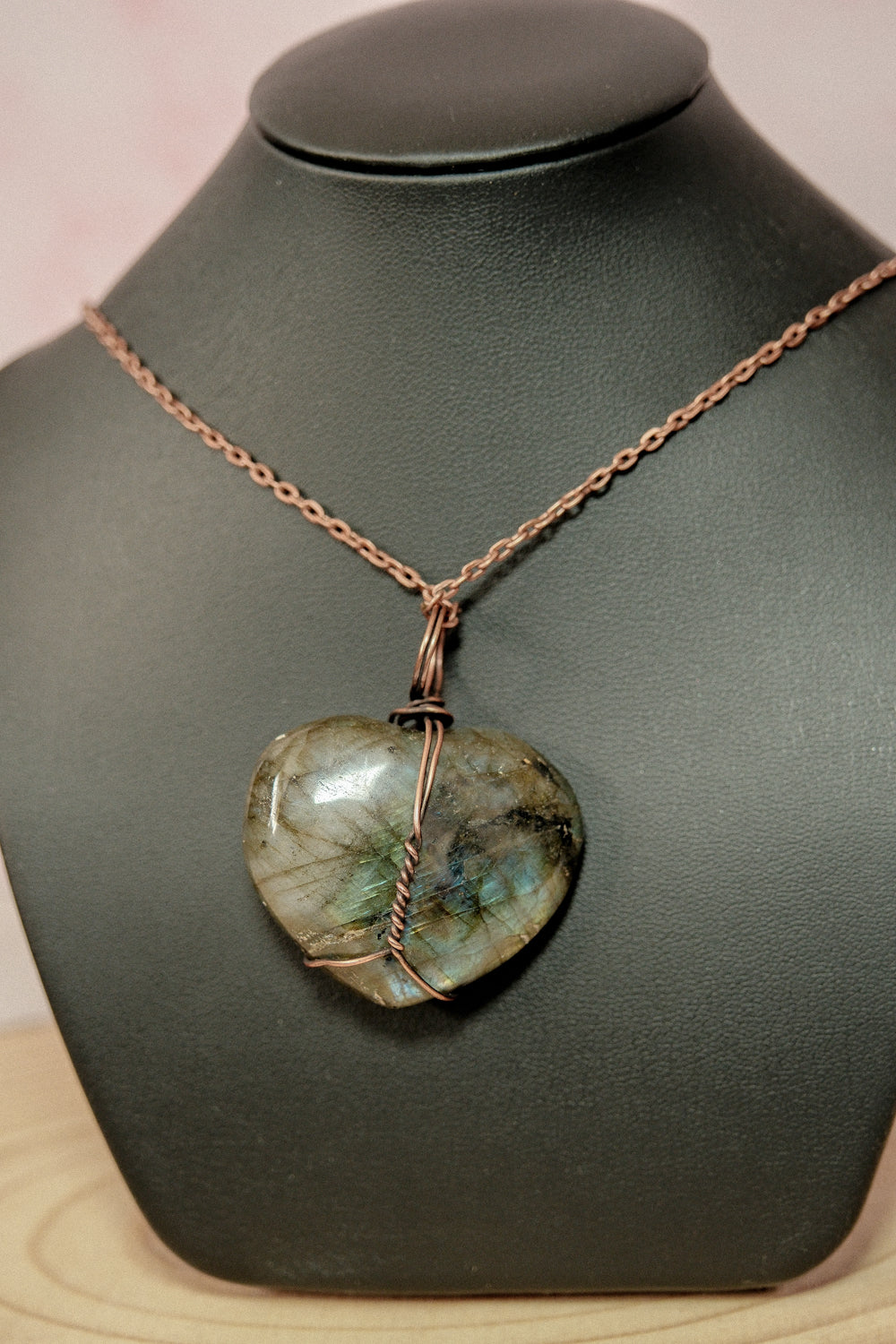 Necklace with a heart-shaped stone pendant on a black mannequin bust.