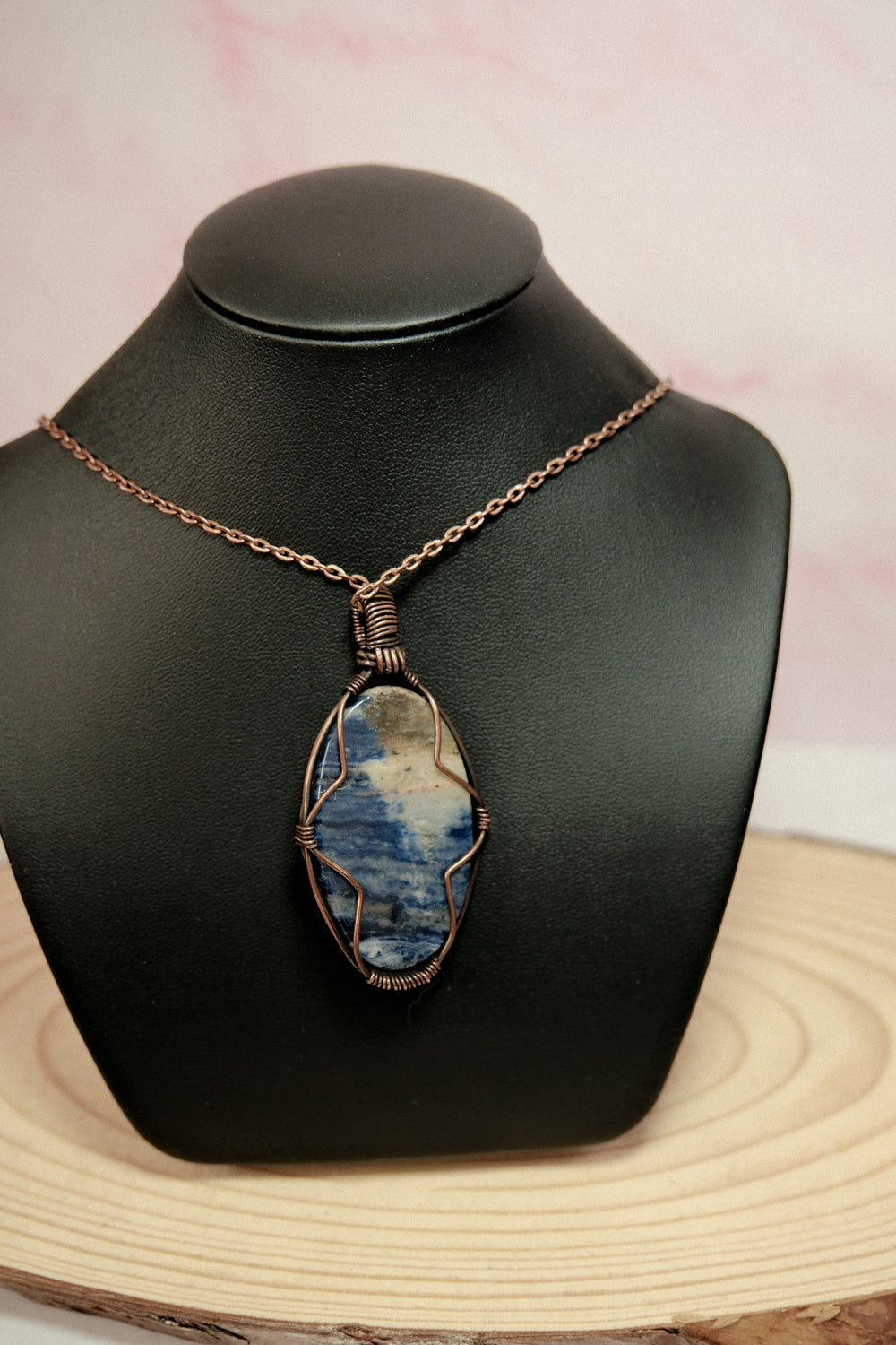 Necklace with a blue stone pendant on a black mannequin bust.