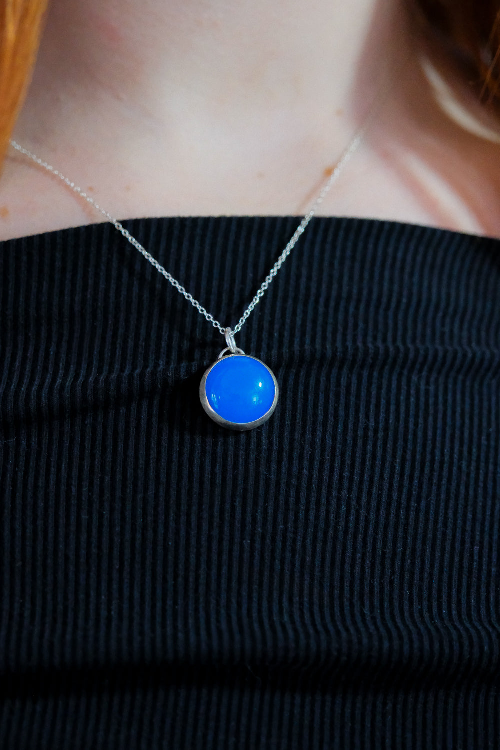 Blue pendant necklace on a black top
