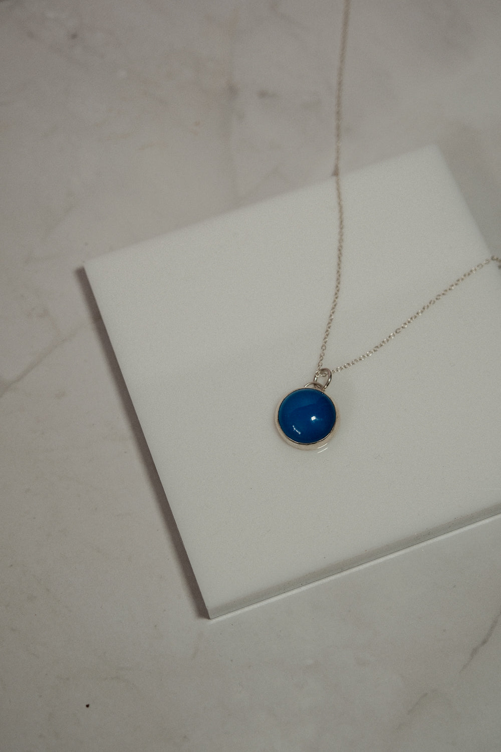 Necklace with a blue pendant on a white surface