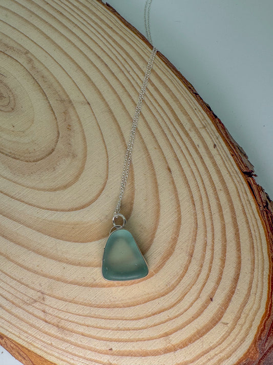 Necklace with a blue sea glass pendant on a wooden surface