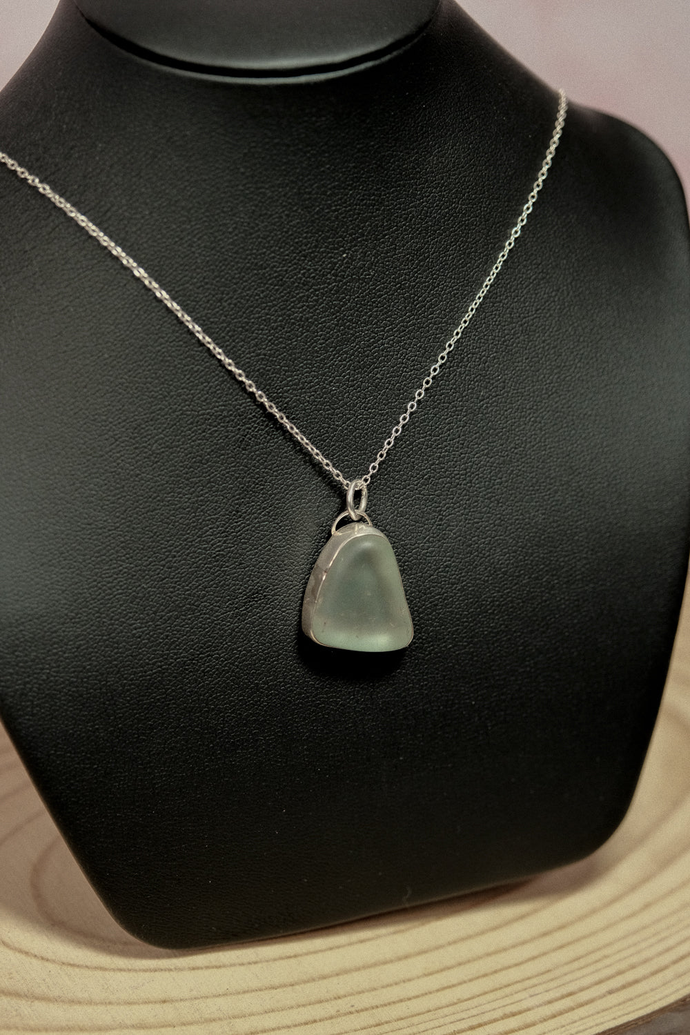 Blue sea glass pendant on black mannequin