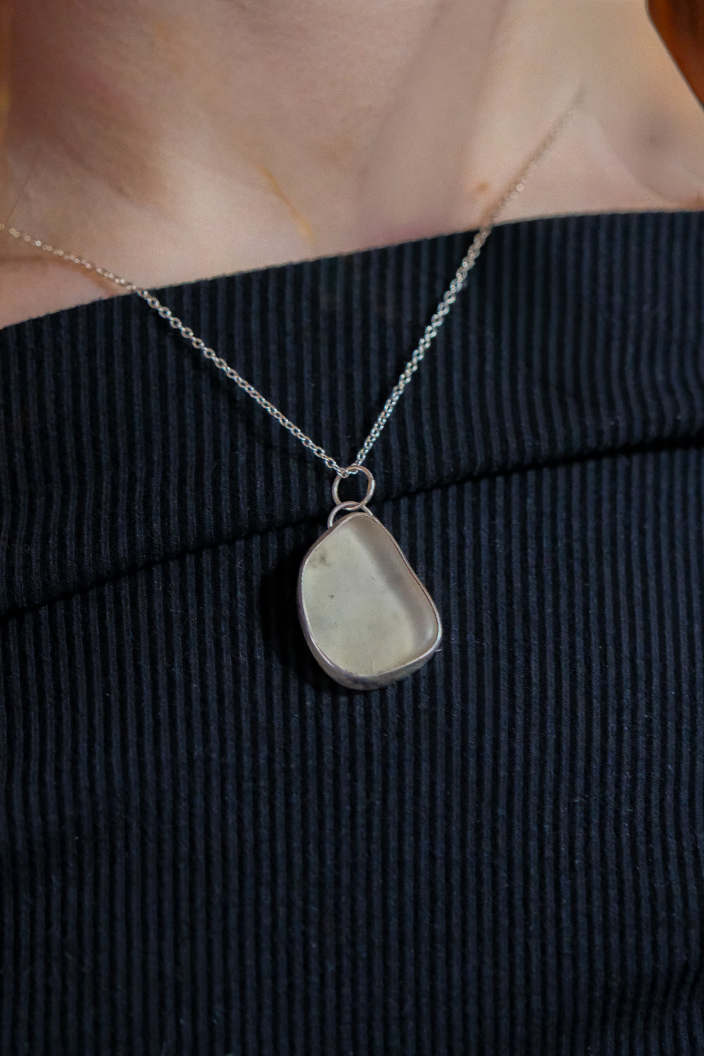Necklace with a pendant worn by a person against a dark background