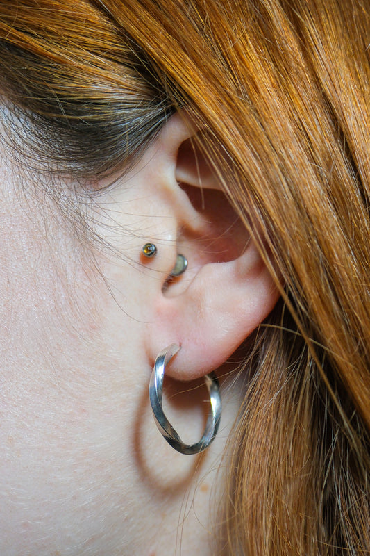 Close-up of an ear with hoop earrings and a small earring.
