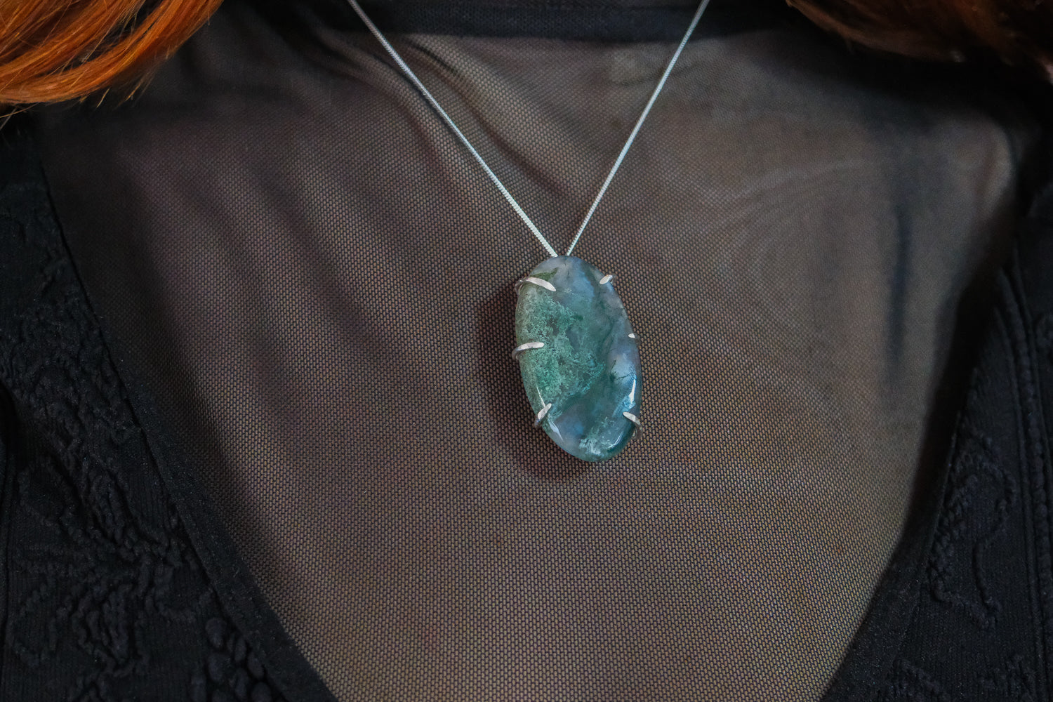 Necklace with a moss agate pendant on a plain background