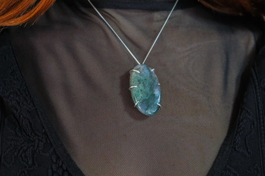 Necklace with a moss agate pendant on a plain background