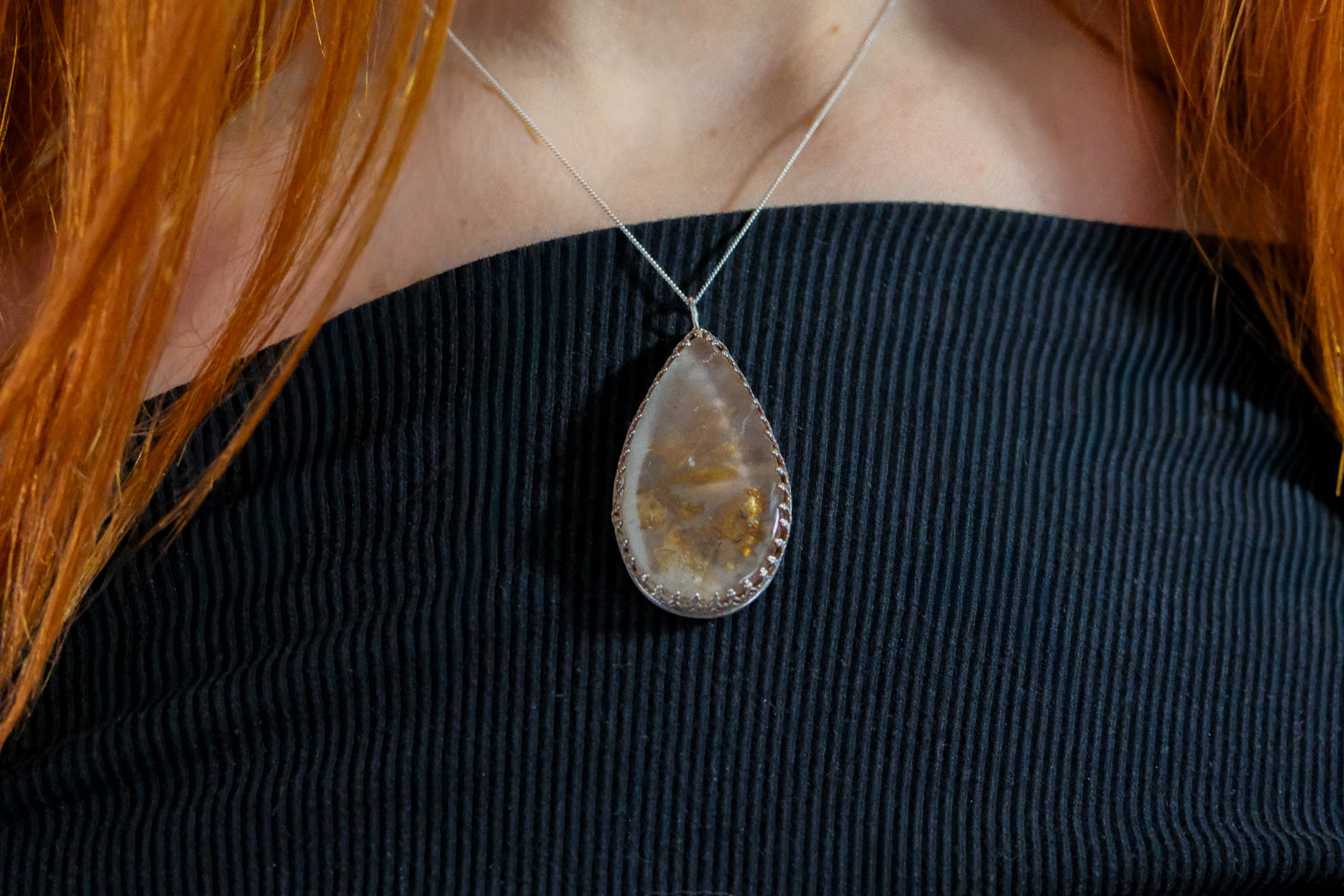 Teardrop-shaped pendant necklace on a person wearing a black top