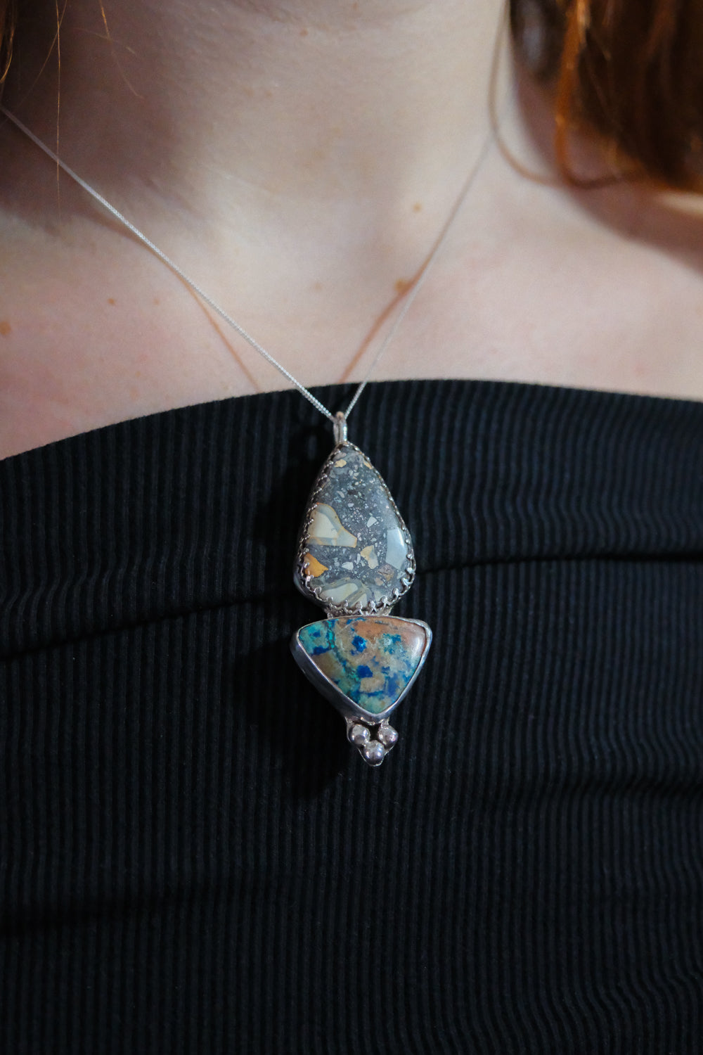 Necklace with a unique pendant worn by a person against a black background