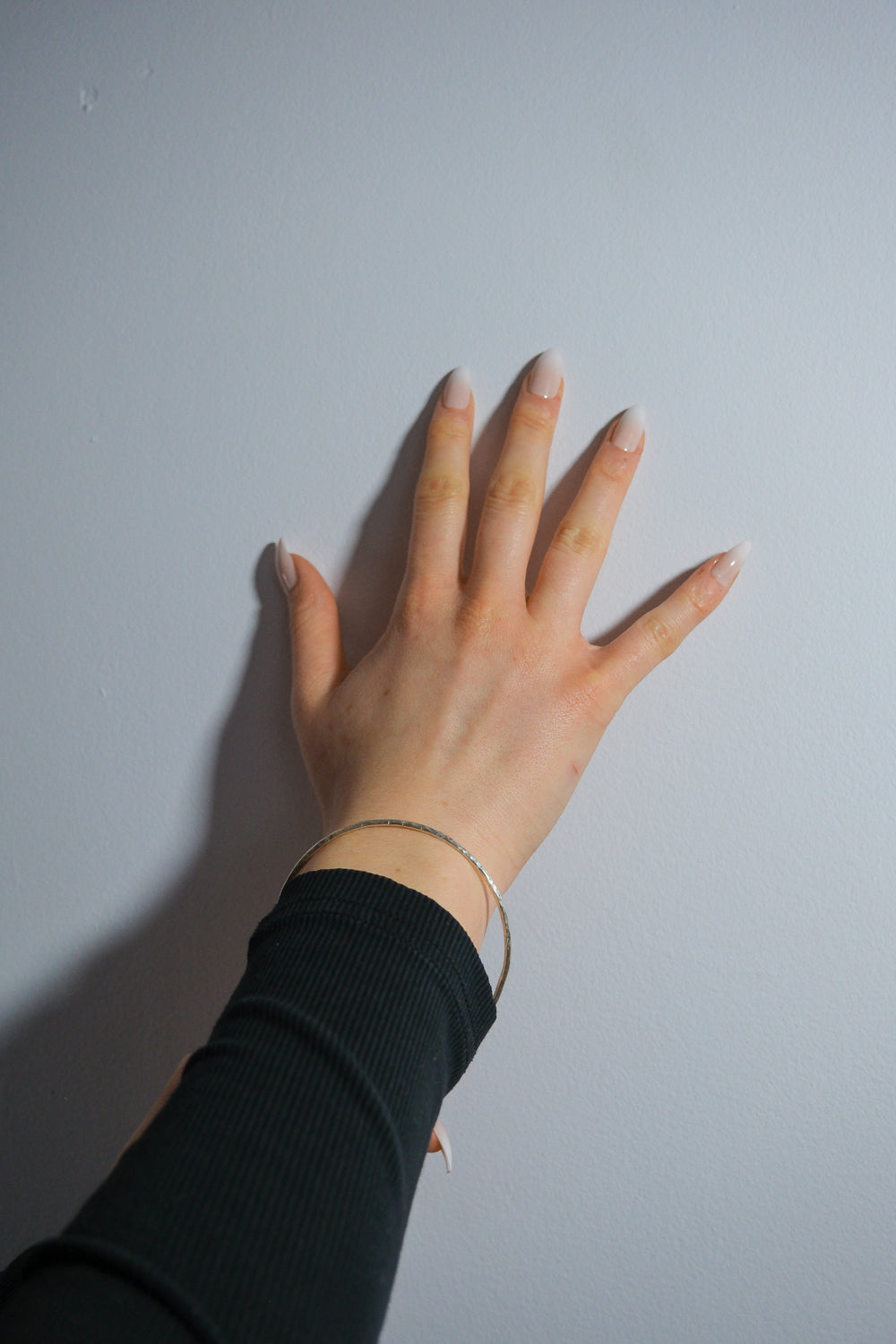 Hand with a silver bracelet on a plain background
