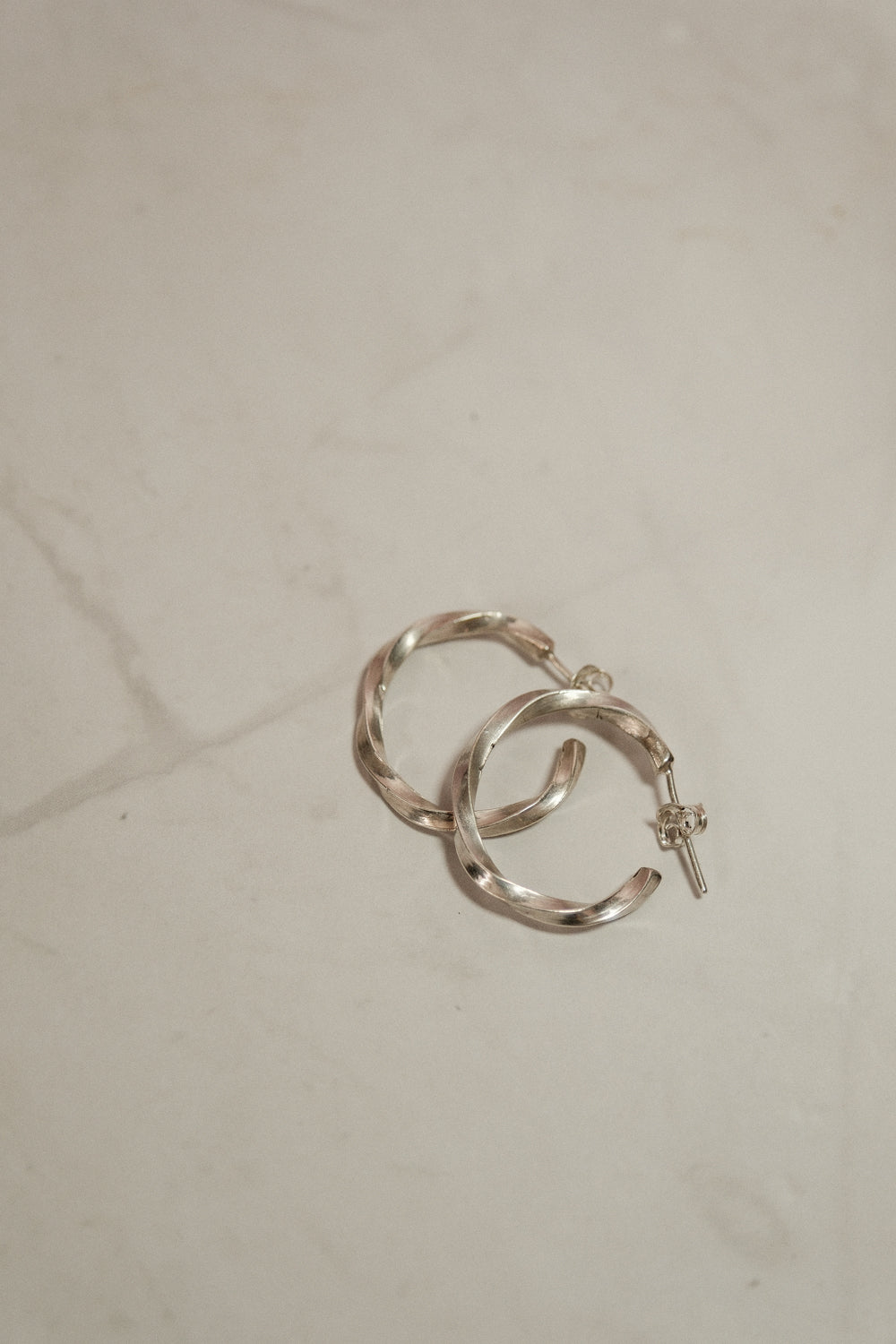 Silver hoop earrings on a white surface