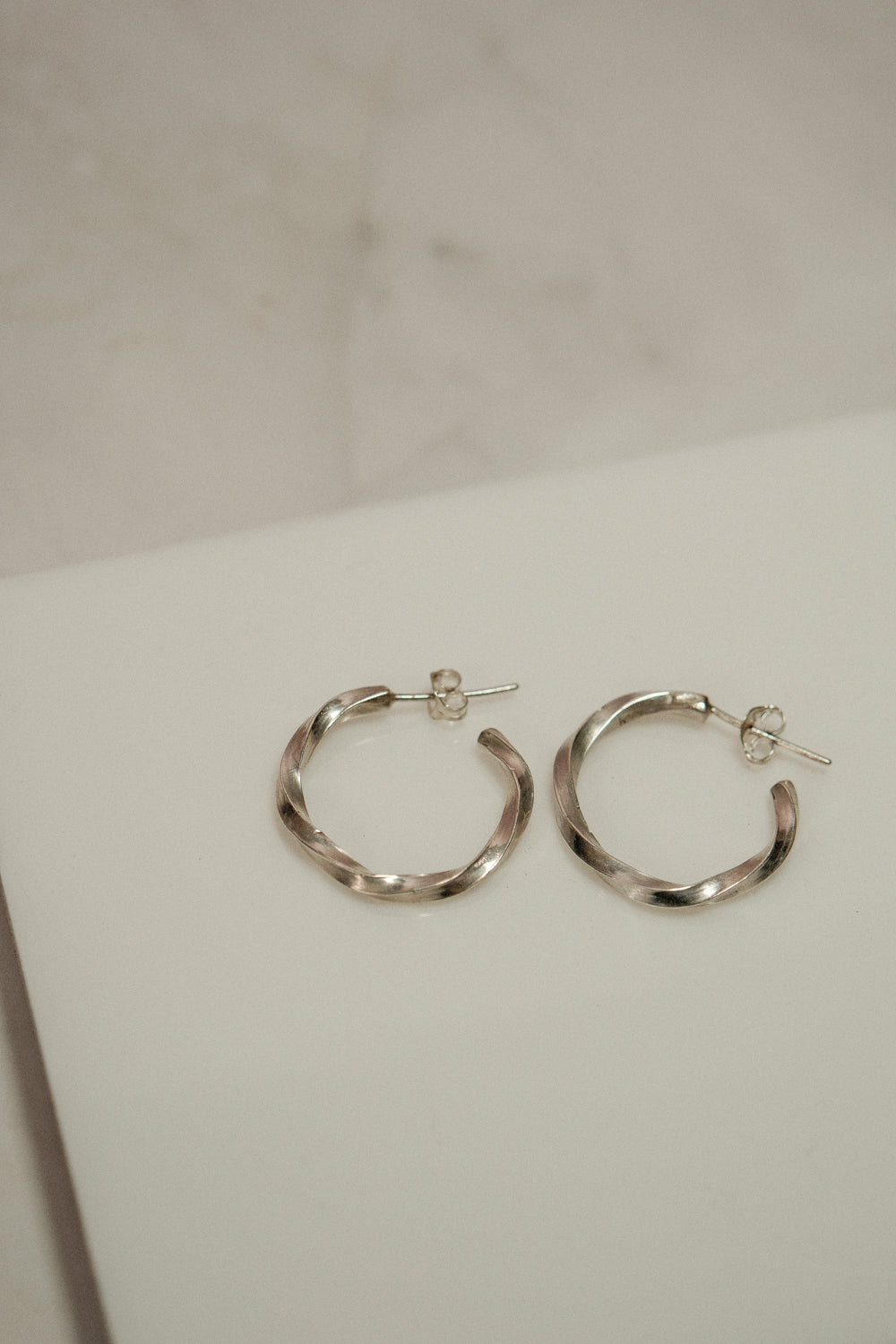 Silver hoop earrings on a white surface