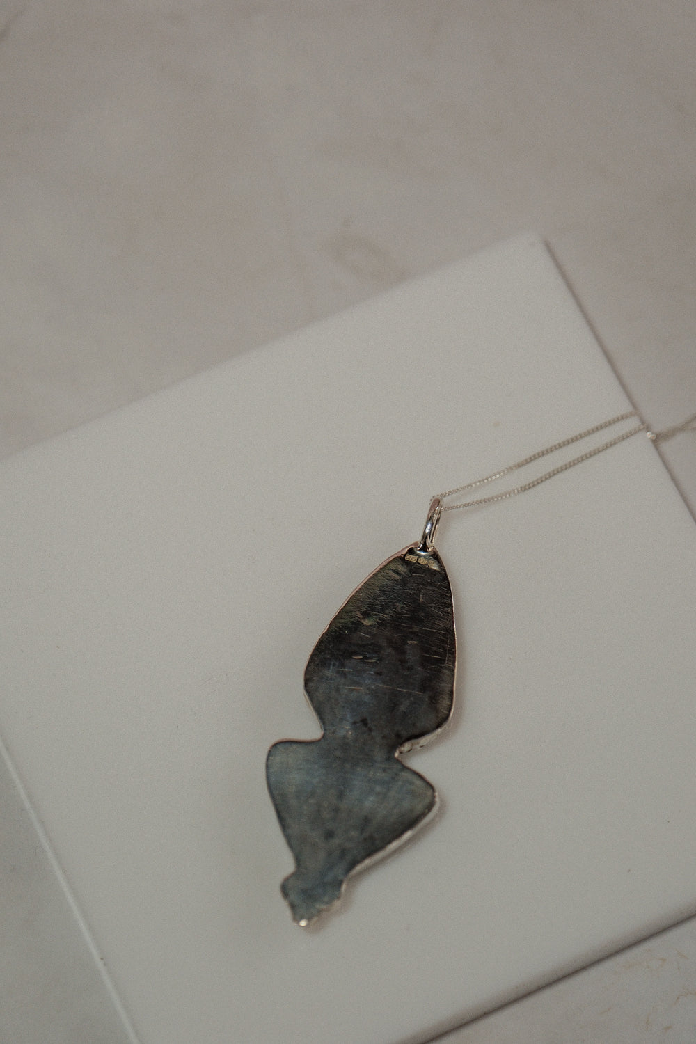 Uniquely shaped pendant on a string against a white background