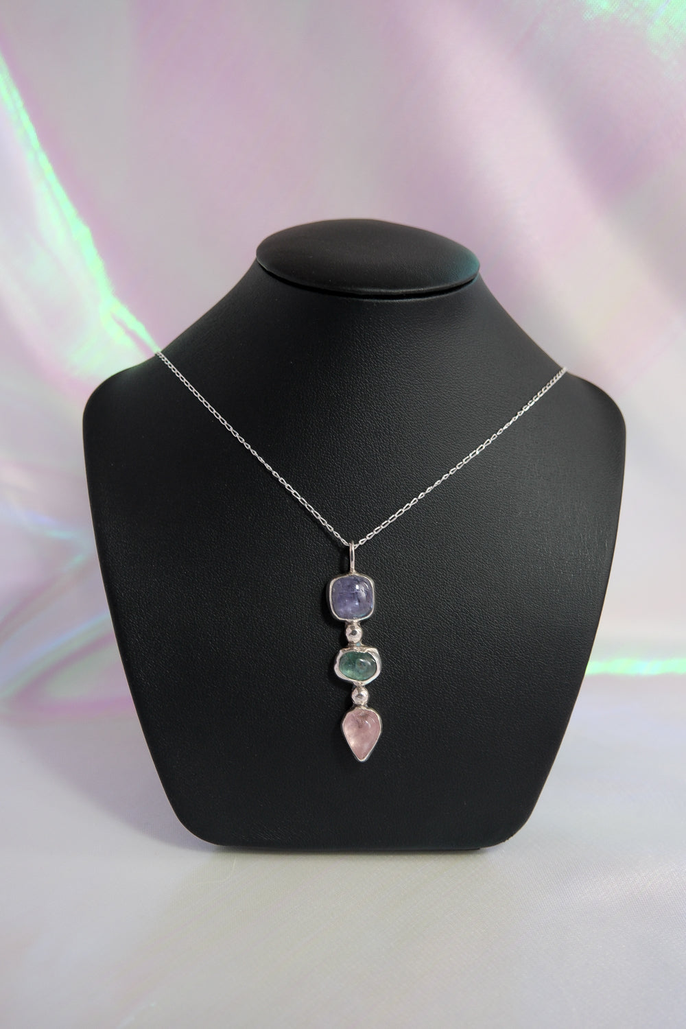 Necklace with multicolored pendant on a black mannequin bust against a light background