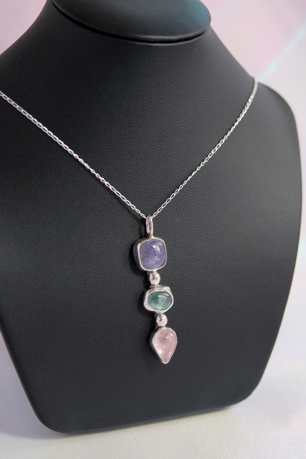 Necklace with multicolored gemstones on a black mannequin bust.