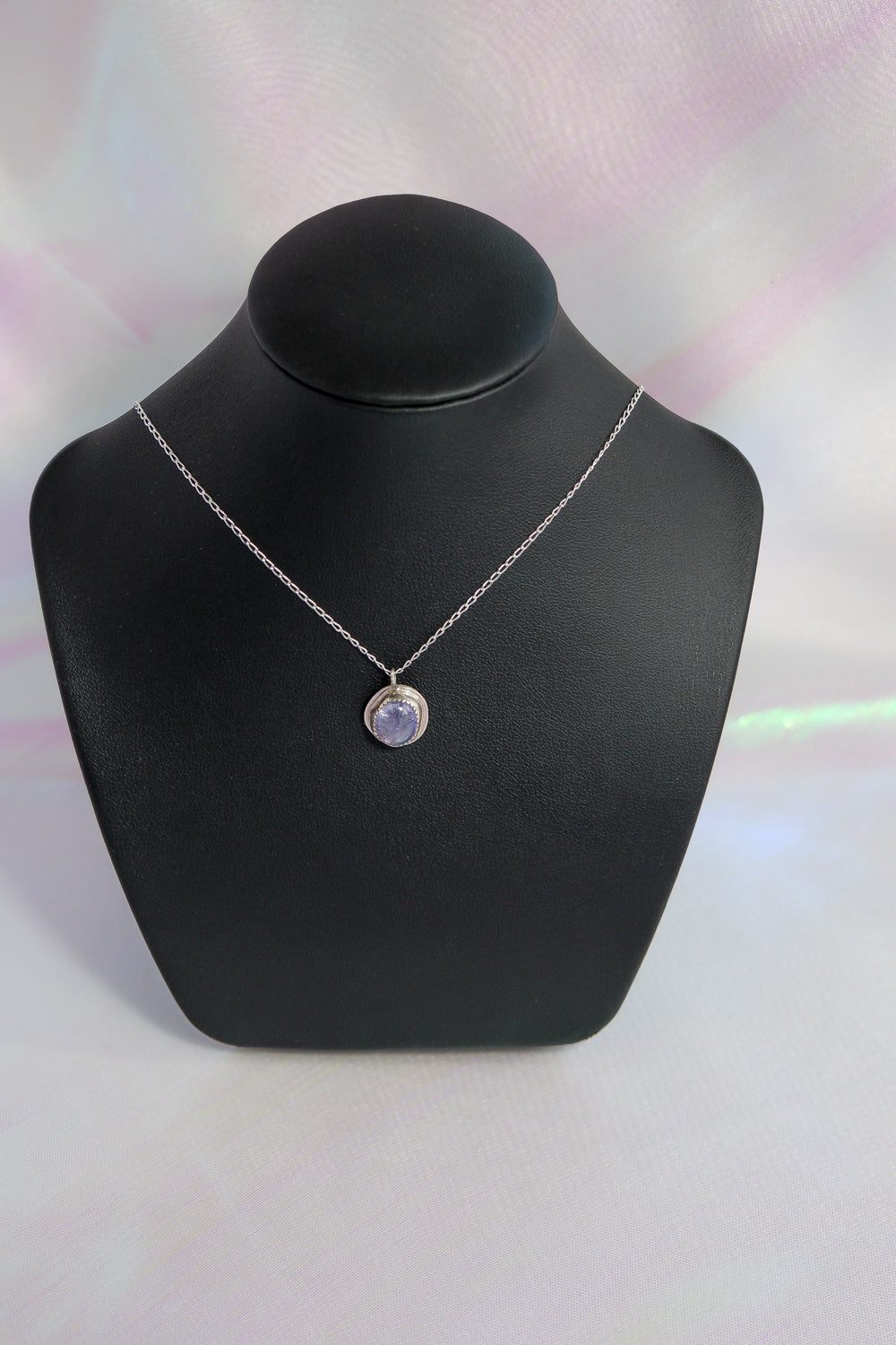 Necklace with a pendant on a black mannequin bust against a light background
