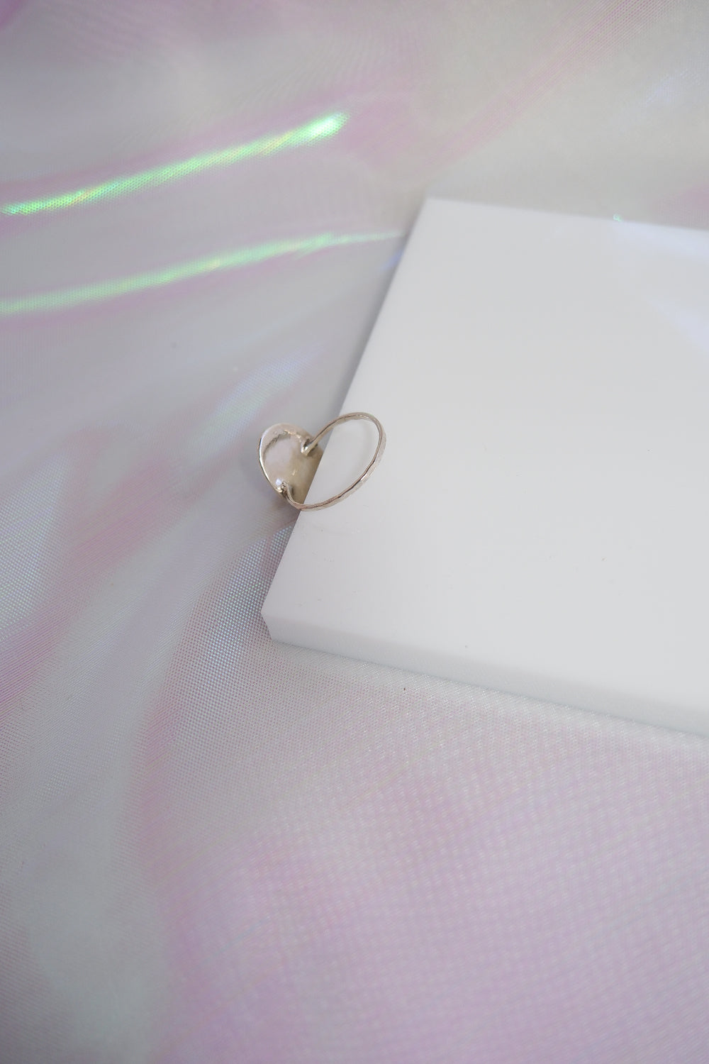 Silver ring on a white surface with a soft, blurred background