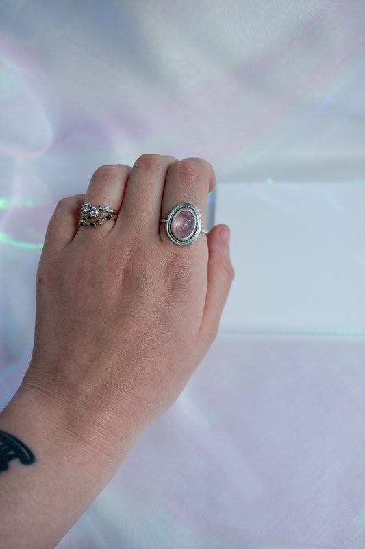Hand wearing two rings with a colorful, blurred background