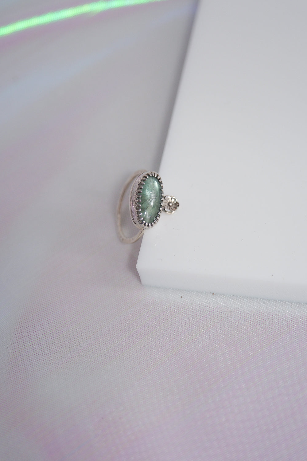 Silver ring with a green gemstone on a white background