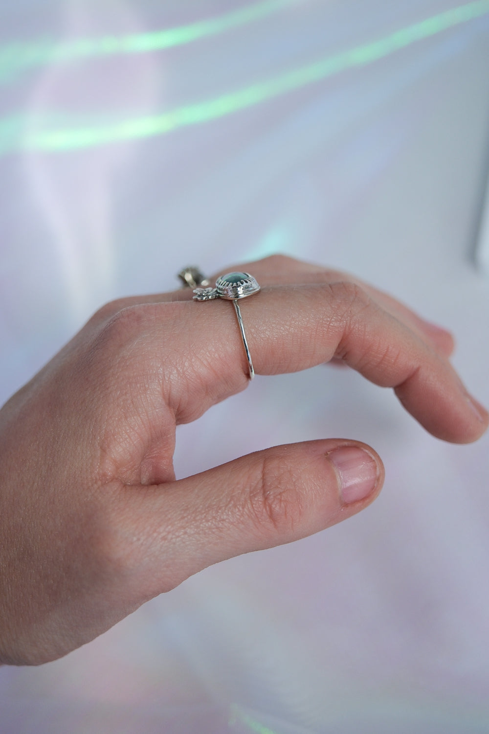 Hand wearing two rings with a soft, blurred background