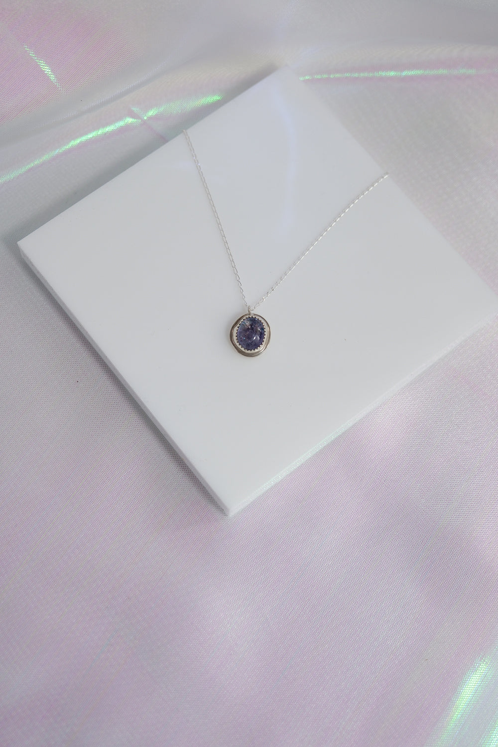 Necklace with a pendant on a white card against a reflective surface