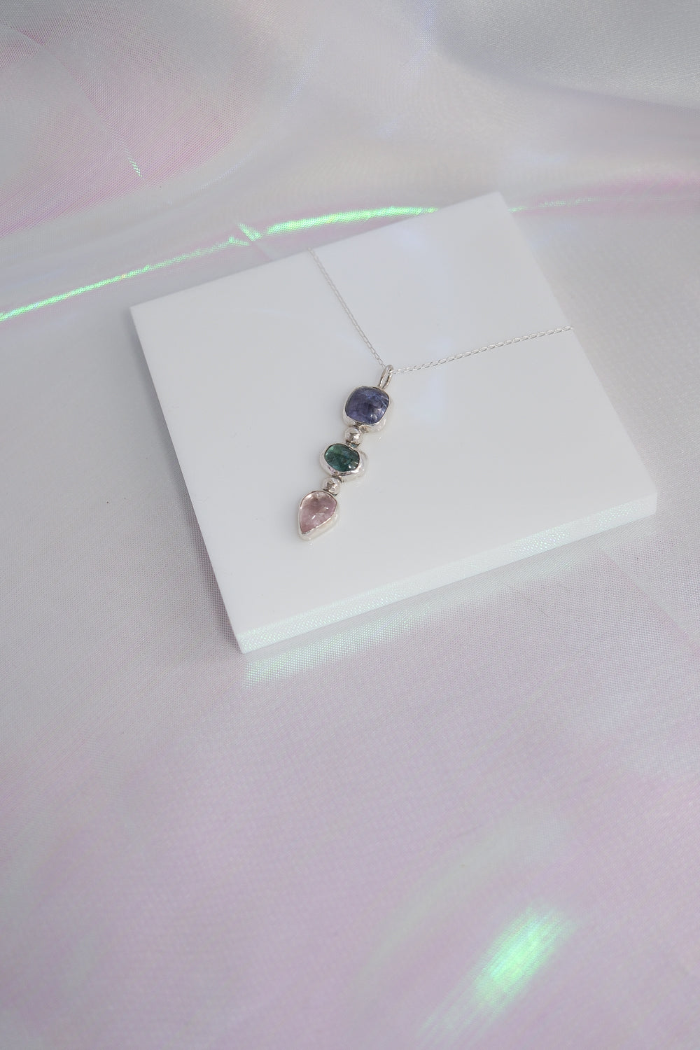 Jewelry pendant with multicolored stones on a white card