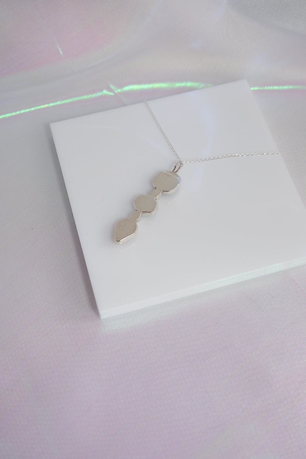 Silver necklace with geometric pendant on a white card