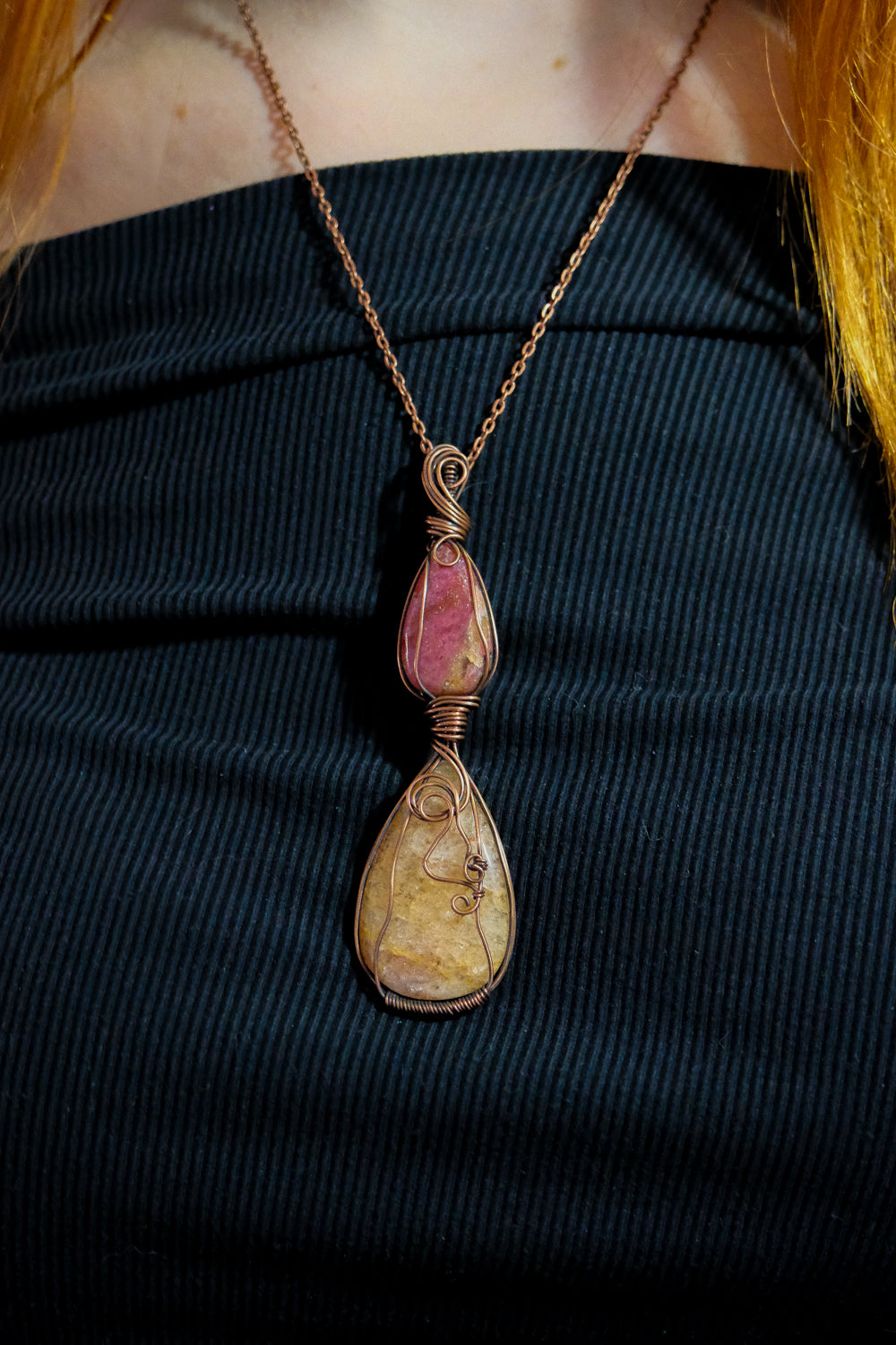 Necklace with a pendant featuring pink and brown stones on a dark background