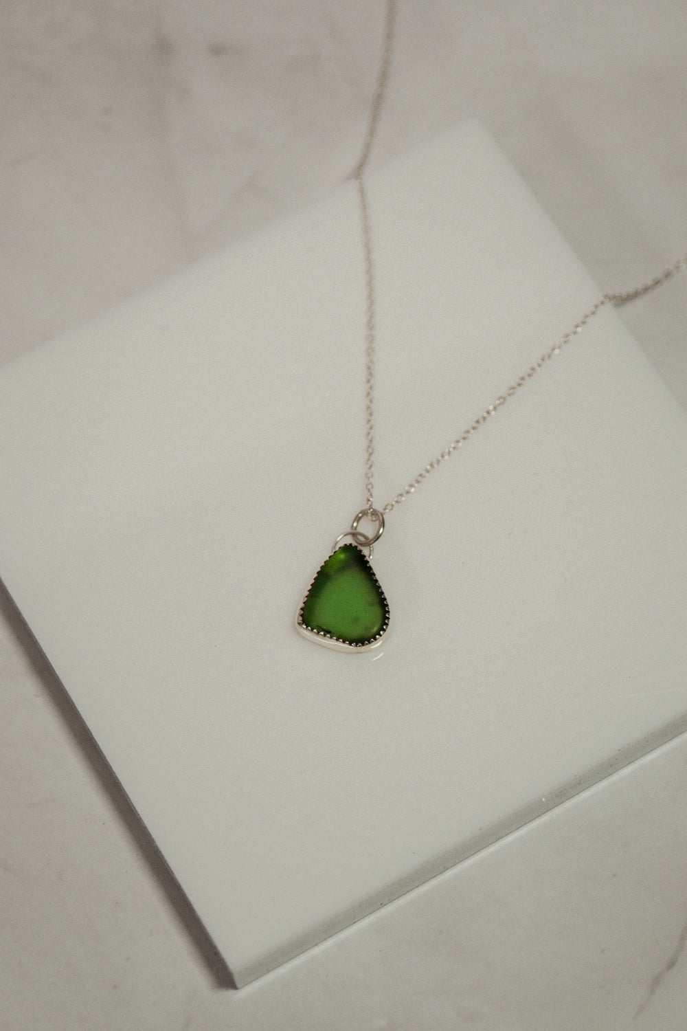 Green pendant necklace on a white box