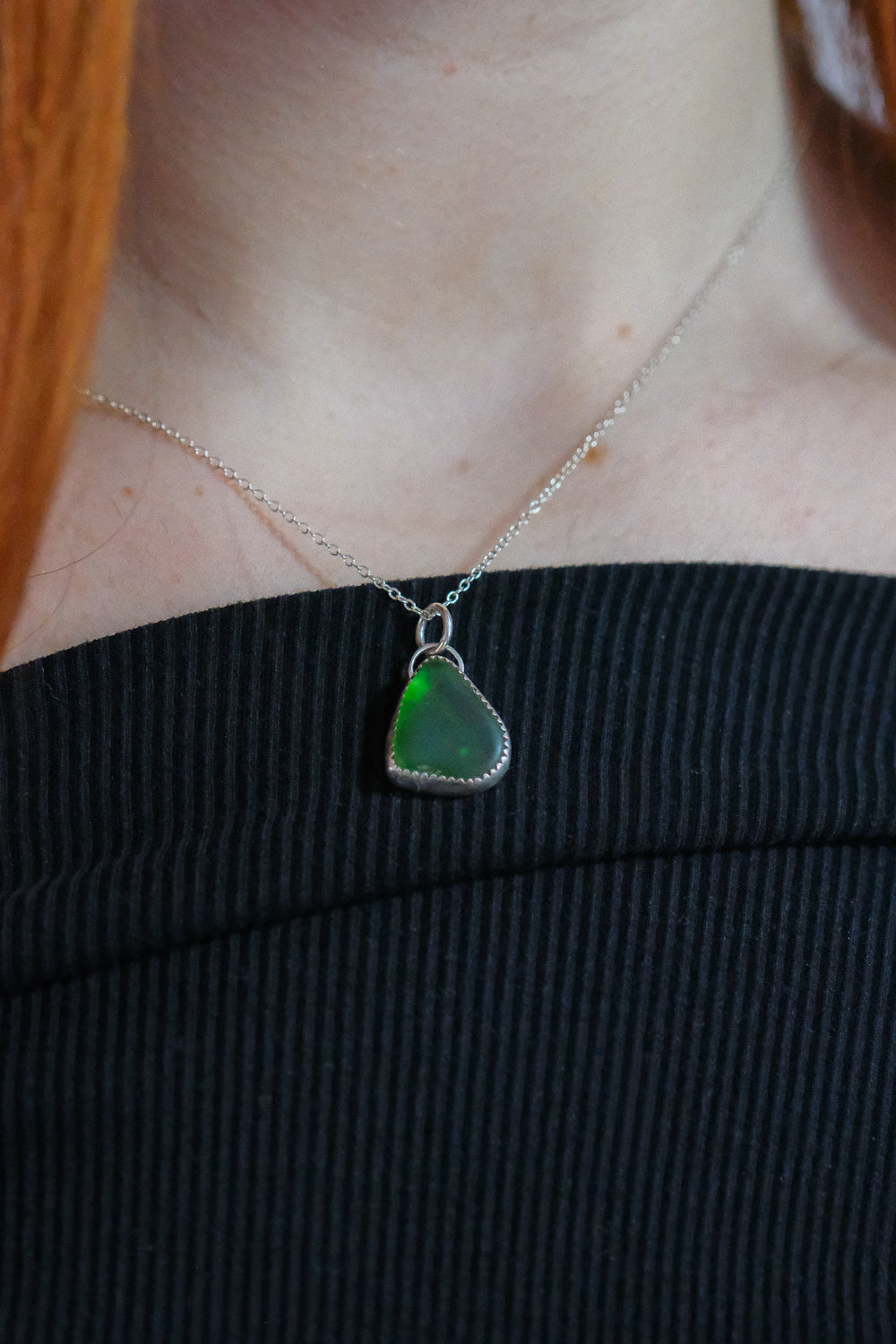 Person wearing a necklace with a green pendant
