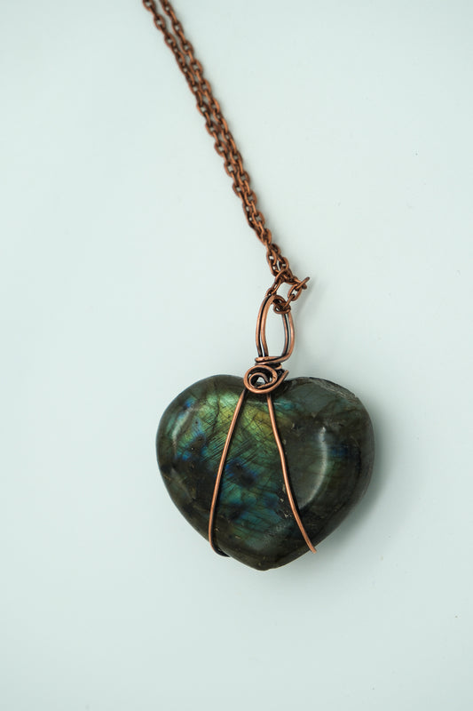 Heart-shaped labradorite pendant on a copper chain against a light background