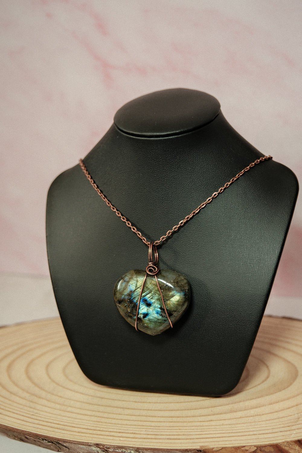 Necklace with a heart-shaped labradorite pendant on a black mannequin bust.