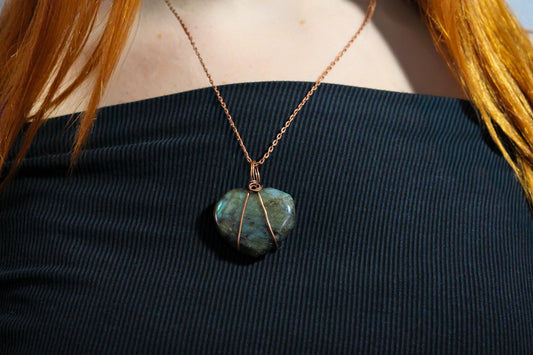 Necklace with a labradorite pendant on a person wearing a black top.