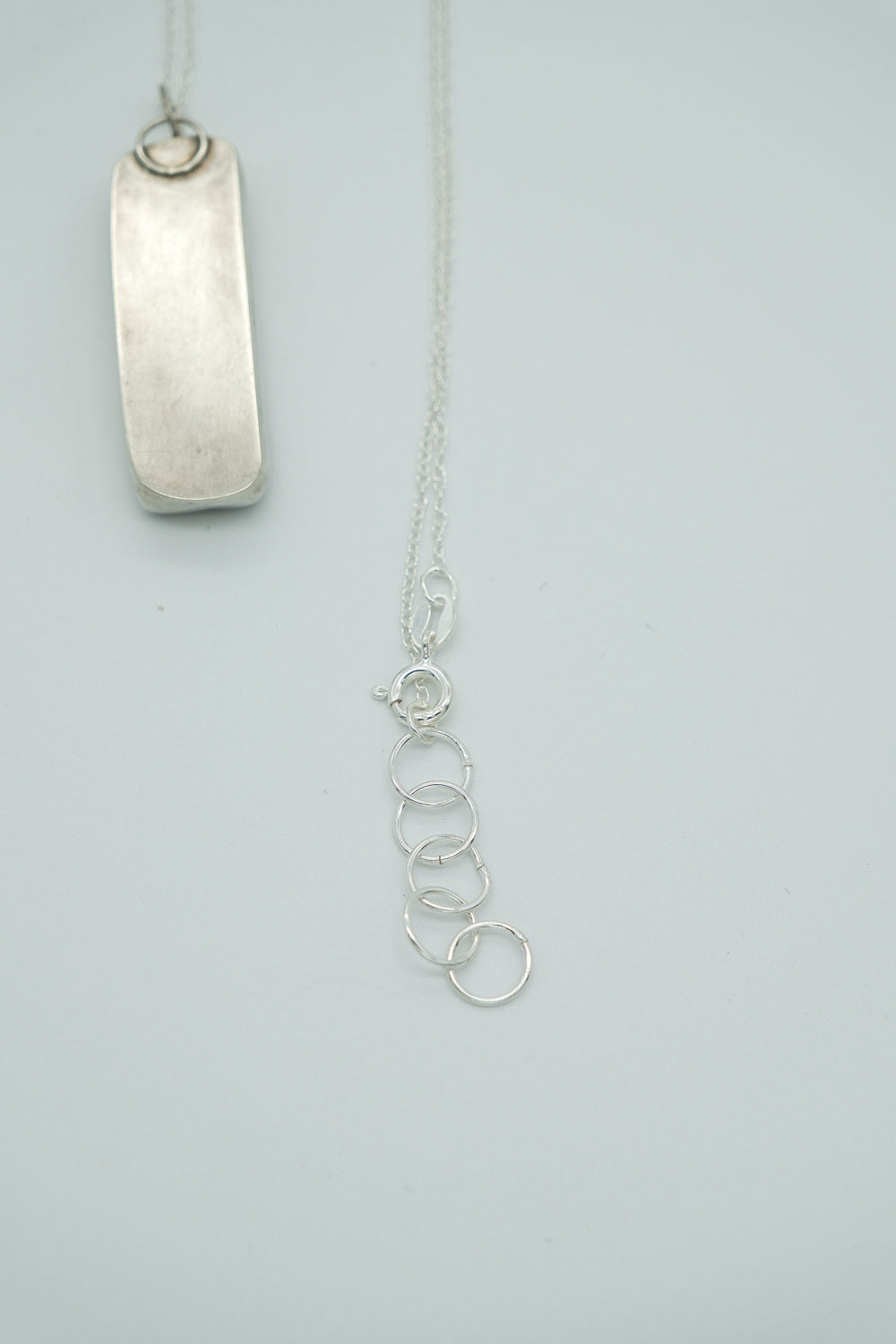 Silver necklace with a pendant on a light gray background