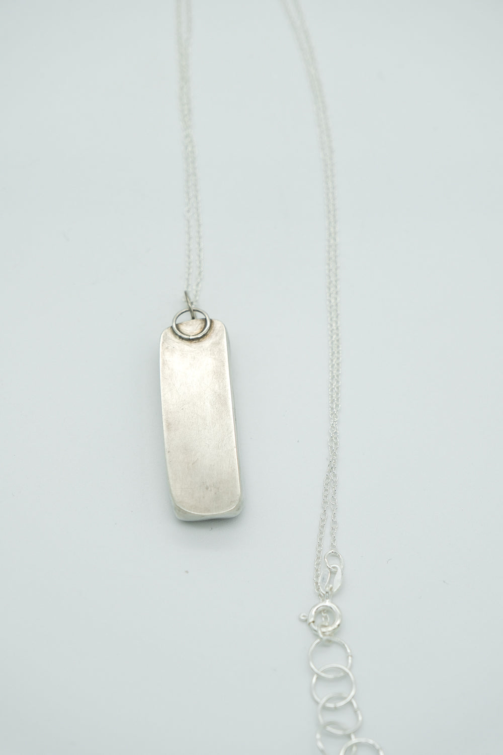 Silver necklace with a pendant on a light gray background