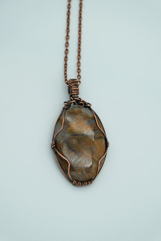 Bronze pendant necklace on a light blue background