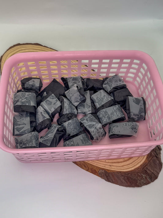 Pink basket filled with black mystery crystals on a white background